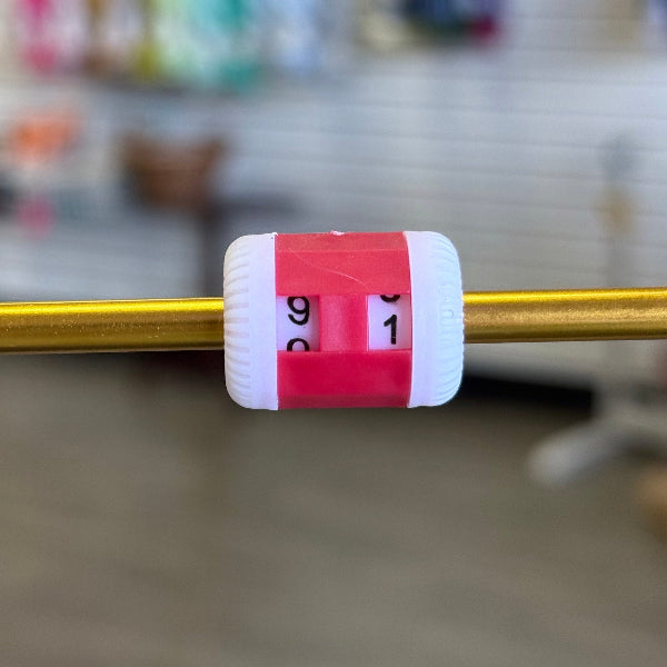red and white analog row counter on a knitting needle
